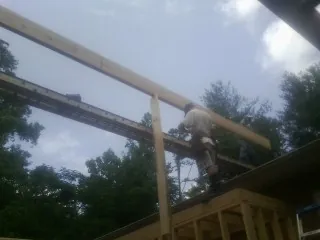 Carpenter setting a ridge beam over a new addition frame — Ice Dam Removal by Roofing Brothers in Swain