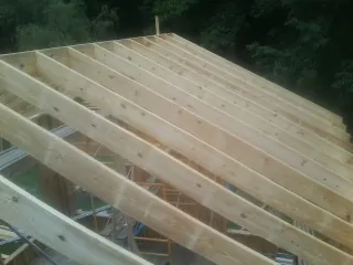 New roof rafters set over an addition before sheathing in Swain