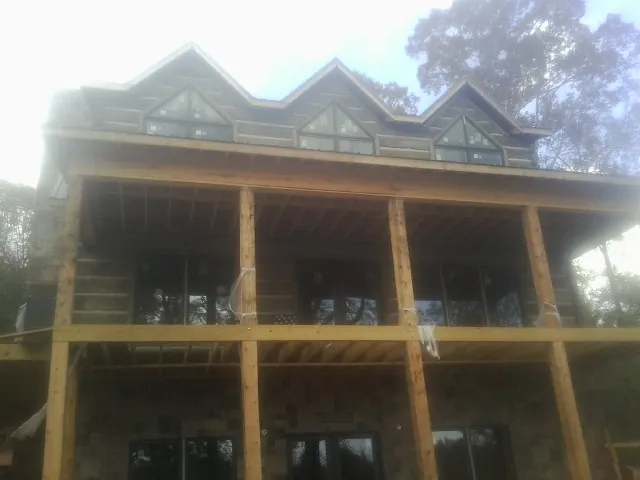 Dormers and porch framing on a large log home under construction — Roof Coating work by our crew in Swain