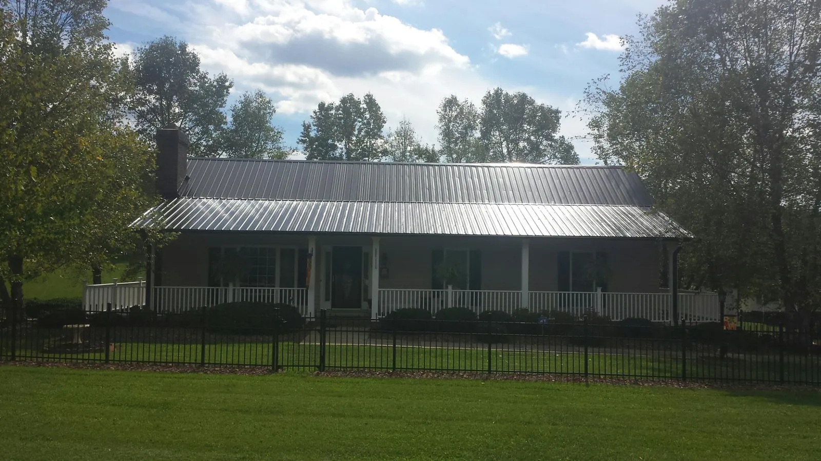 Gray metal roof on a brick ranch with a full width front porch — Gutter Guard Installation work by our crew in Swain